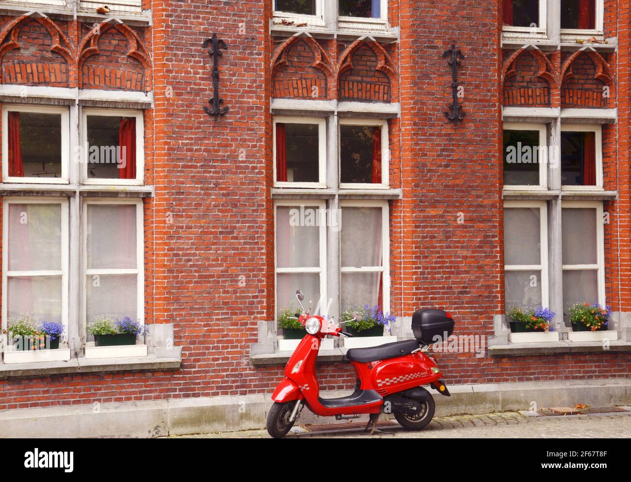 BRUGES, BELGIO, EUROPA, 1ST LUGLIO 2017. Un bellissimo scooter rosso d'epoca parcheggiato fuori da una bella casa nelle strade di Bruges, BELGIO Foto Stock