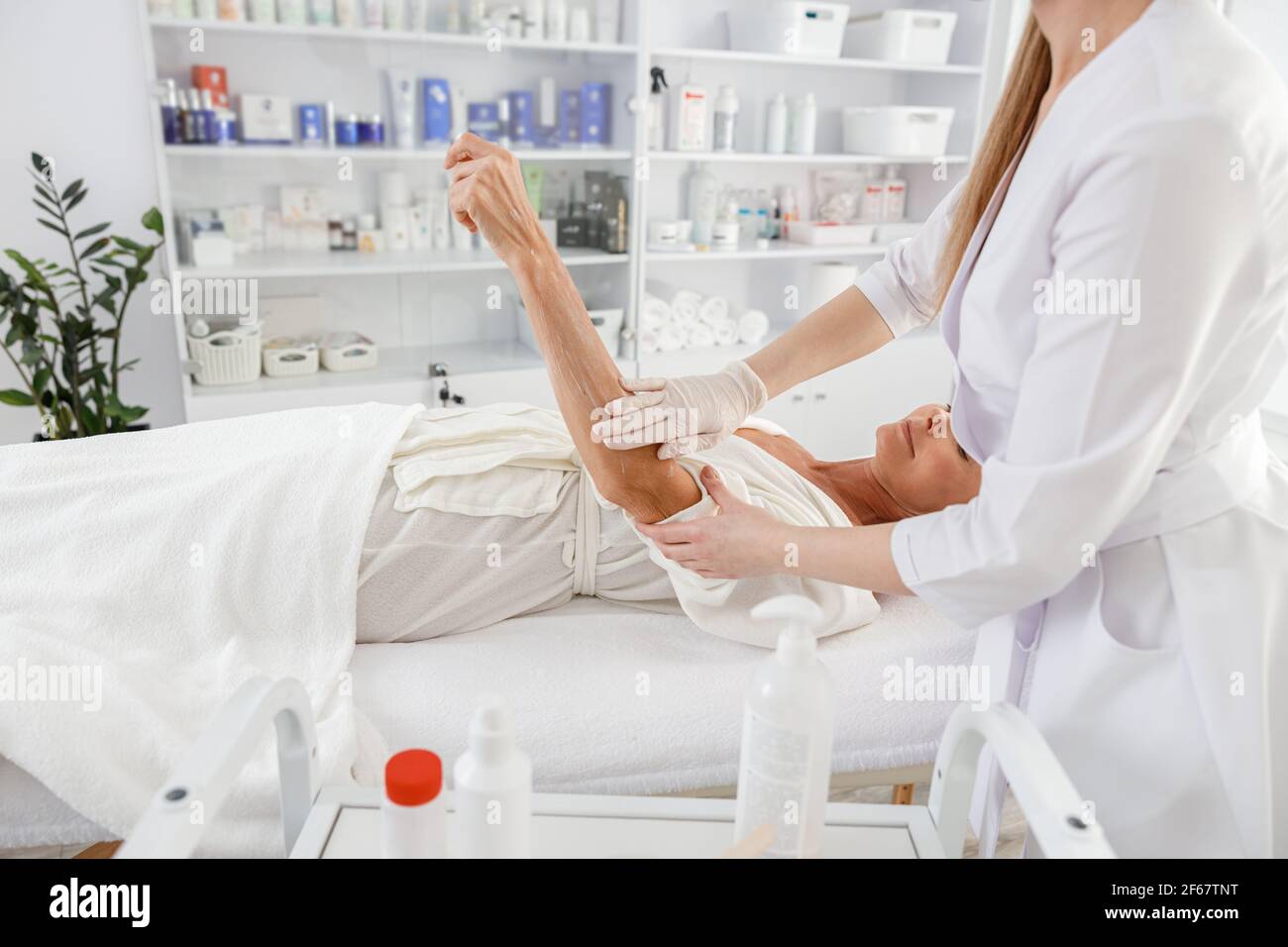 La donna anziana è sdraiata sulla schiena, ottenendo il massaggio di sollevamento. Massaggio di bellezza. Concetto di benessere, bellezza e relax Foto Stock
