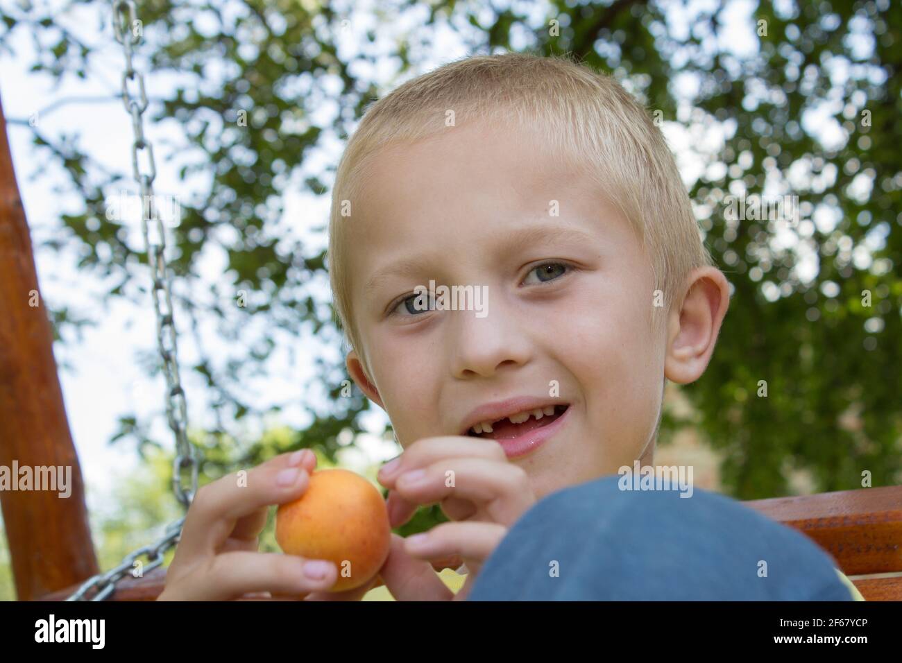 ritratto di un ragazzo senza denti seduto su una panchina Foto Stock