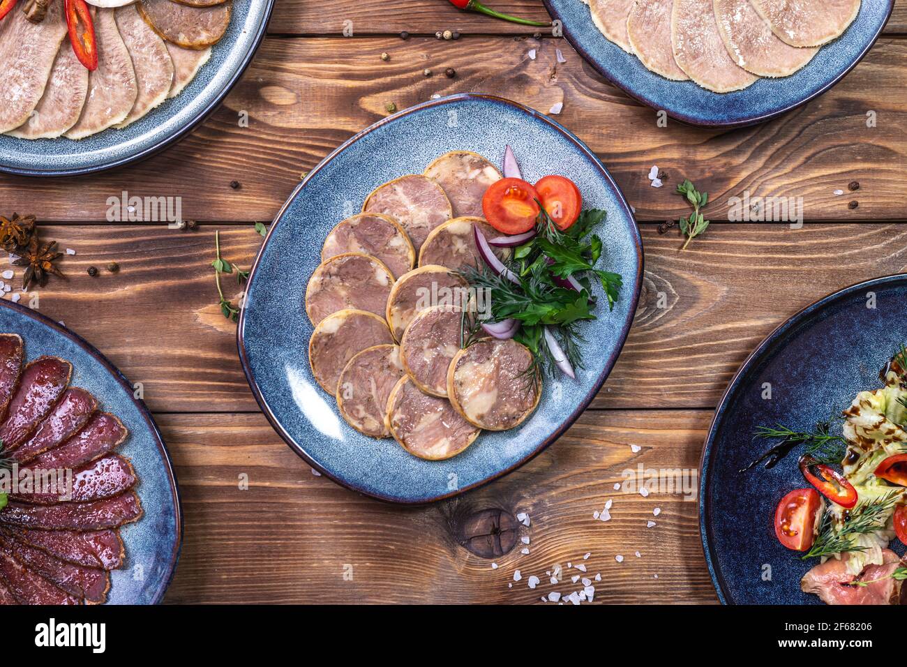 Tagli di carne e salsiccia, aglio, peperoncini, pomodori e altre spezie su fondo marrone di legno. Servizio ristorante. Foto Stock