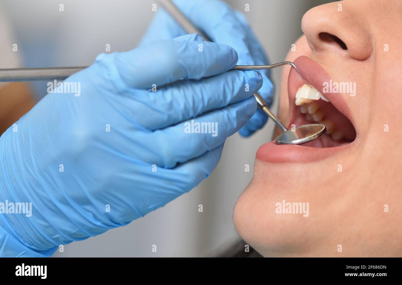 Dentista controlla i denti femmina con attrezzi dentali, primo piano Foto Stock