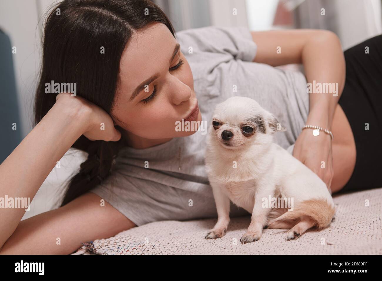 Primo piano di una donna che bacia il suo piccolo e divertente chihuahua cane Foto Stock