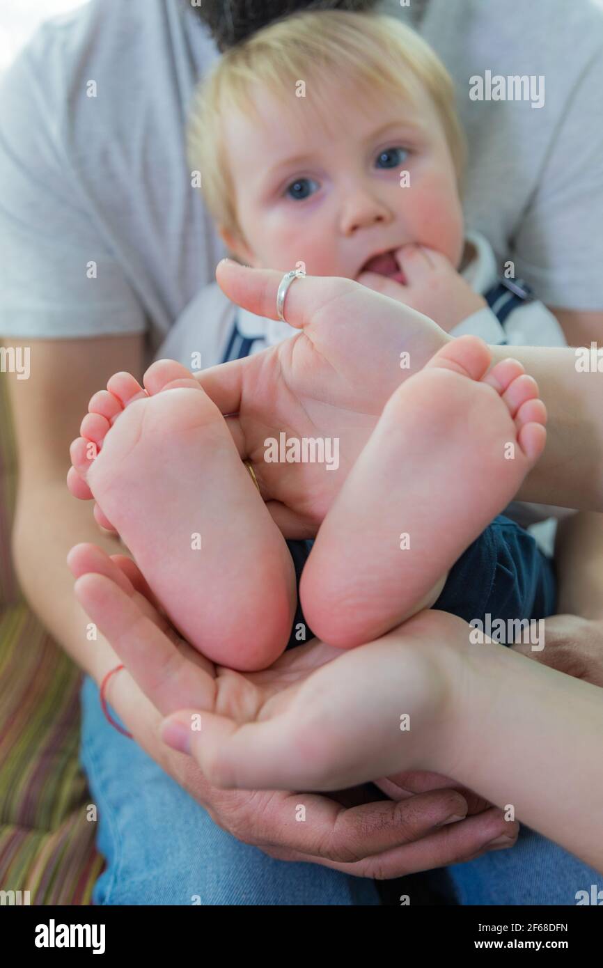 Tutta la famiglia, i genitori e i bambini tengono i tacchi del bambino nel palmo delle mani. Foto Stock