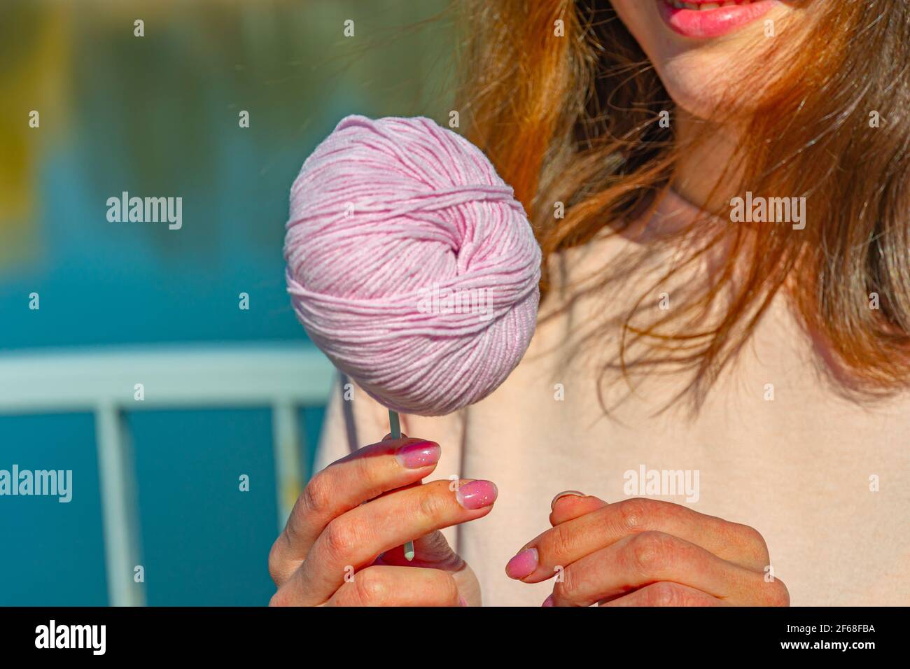 Ragazza con una palla di filo su aghi da maglieria Foto Stock