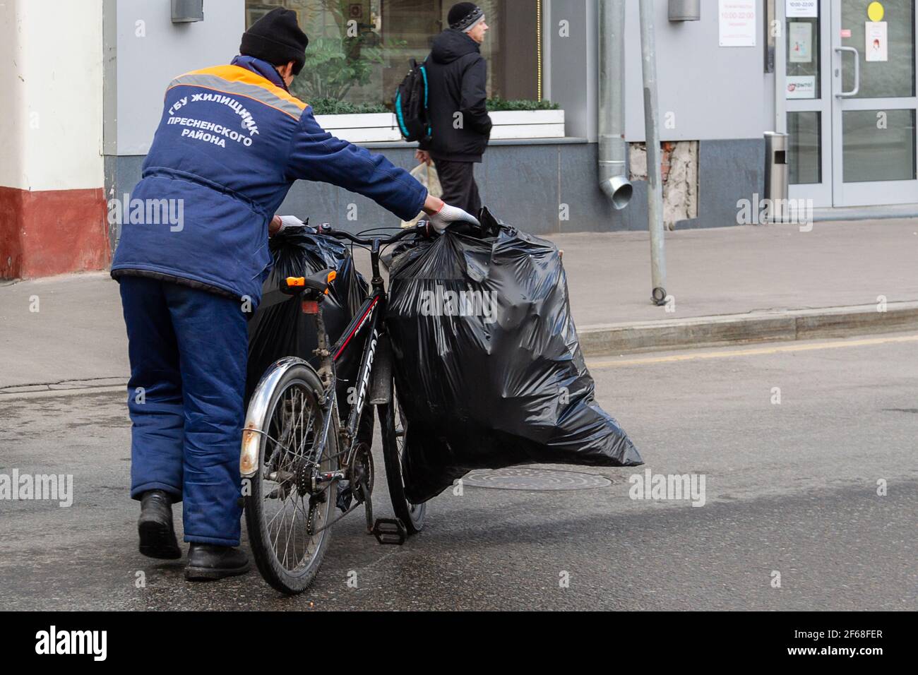 MOSCA, RUSSIA, 03.27.2021 Primavera spazzatura pulizia da parte dei servizi  comunali della città. Il lavoratore in abbigliamento da lavoro trasporta  borse da bici con rifiuti Foto stock - Alamy