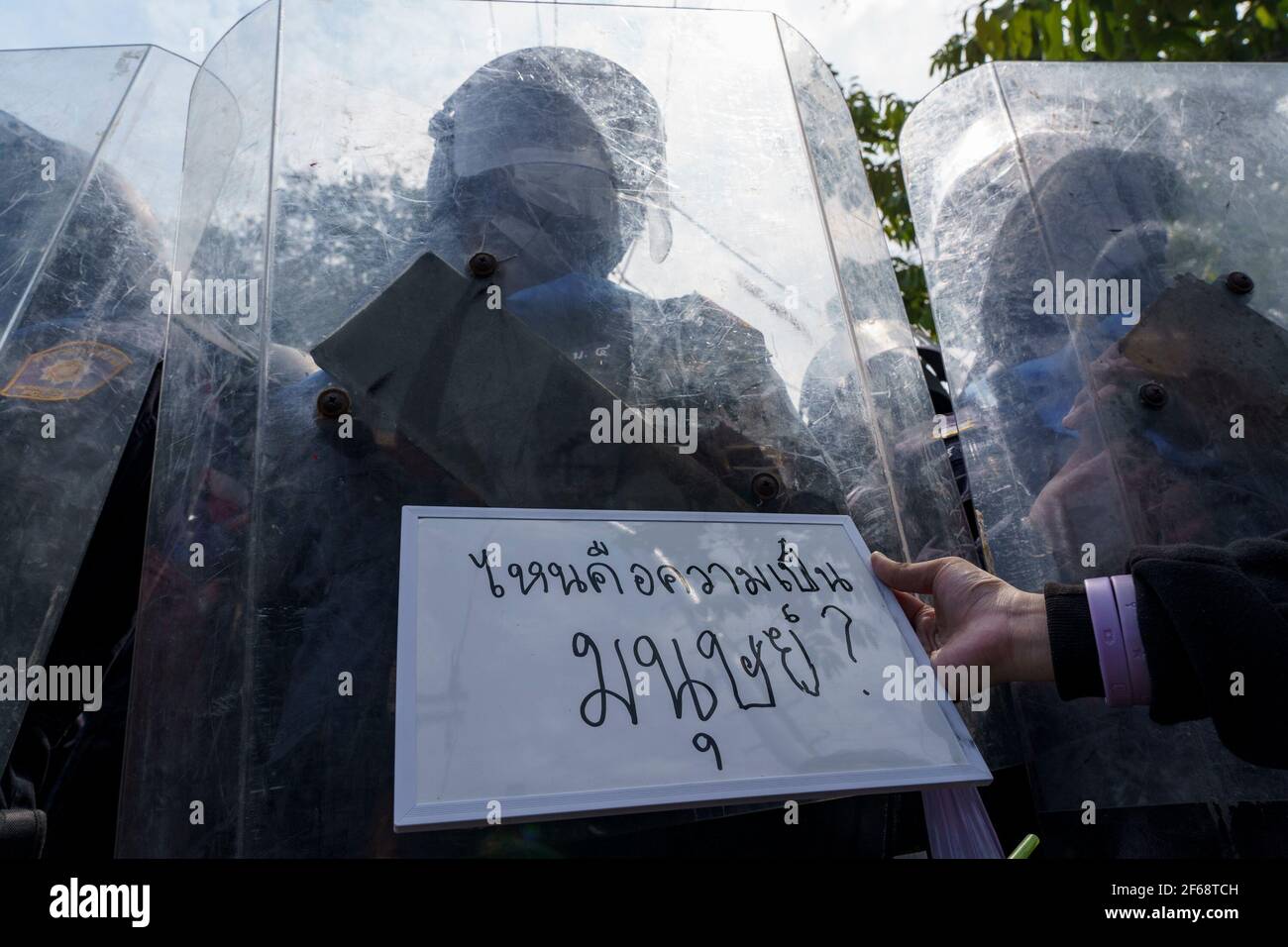 Bangkok, Thailandia. 30 Marzo 2021. Un protestore che mostra un cartello che dice: "Hai ancora l'umanità dentro?" di fronte al controllo della folla che controlla la dimostrazione. I manifestanti pro-democrazia si sono riuniti di fronte alla casa di governo della Thailandia per protestare dopo che il governo thailandese ha violato con forza una protesta pacifica chiamata 'Thalufah Village'. Le idee principali di questa protesta erano di chiedere il rilascio di leader pro-democrazia che sono in custodia a causa della legge lèse-majesté articolo aka 112. (Foto di Watcharawit Phudork/SOPA Images/Sipa USA) Credit: Sipa USA/Alamy Live News Foto Stock