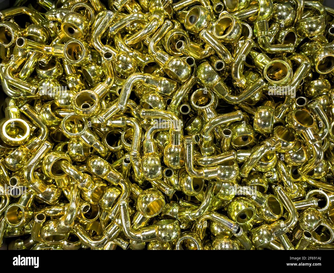 molte parti in metallo color oro, zincate gialle, raccordi per tubi piegati e una boccola saldata, produzione di serie, industria metallurgica compo automobilistico Foto Stock