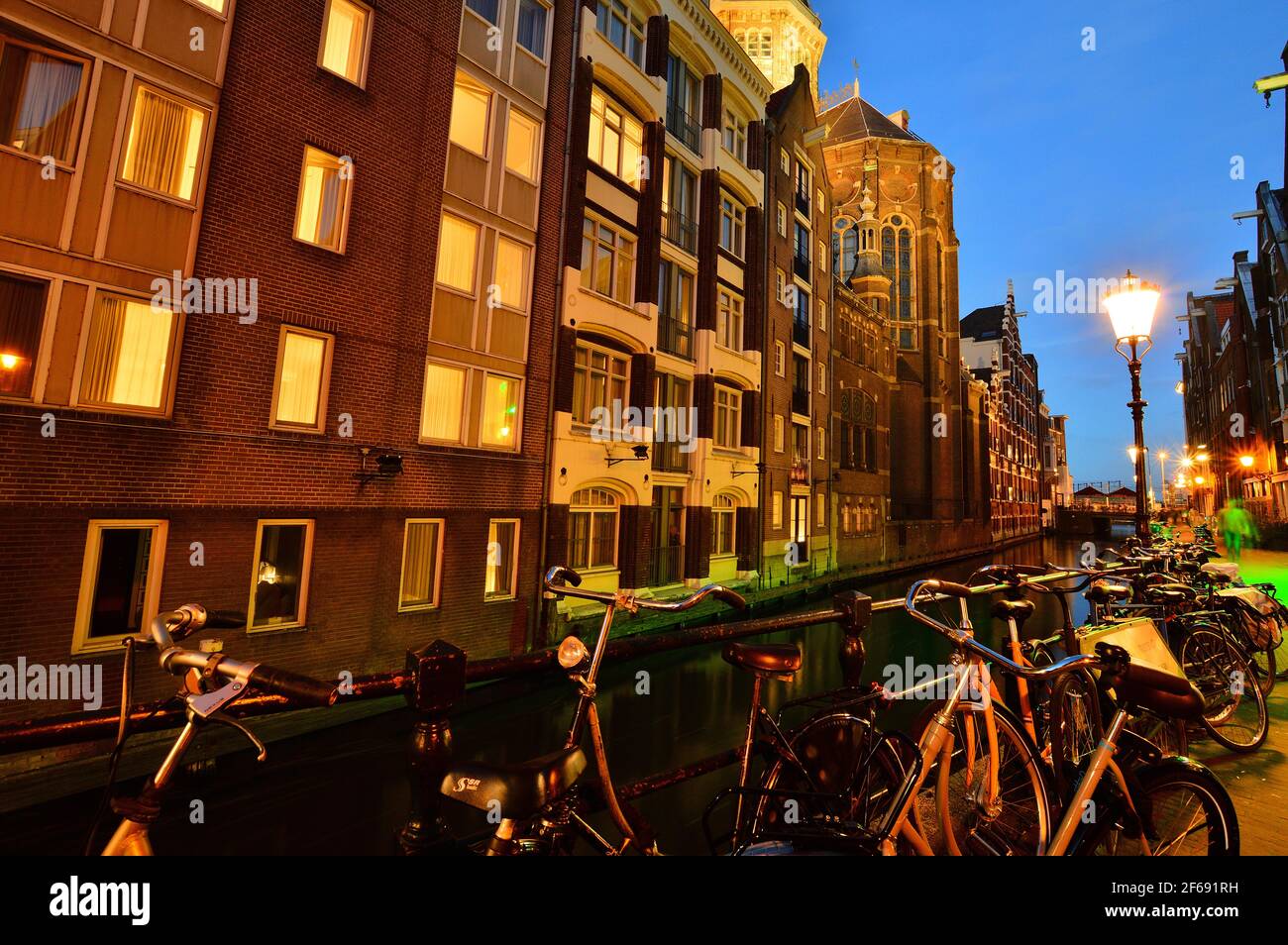 Biciclette sul canale di Amsterdam, Paesi Bassi di notte illuminate da luci colorate. Notte. Bicykle. Foto Stock