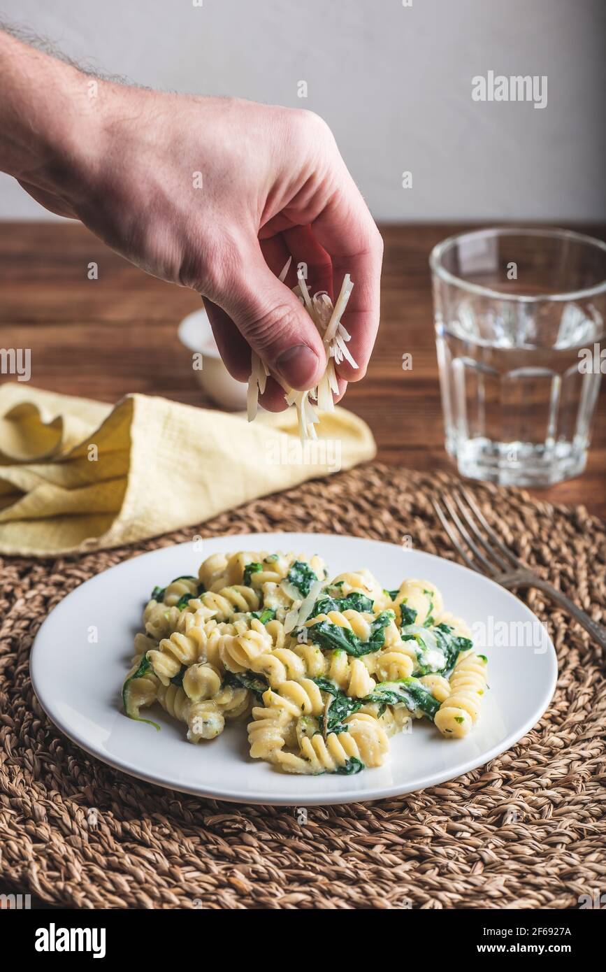 Pasta di fusilli con spinaci e ricotta guarnita con parmigiano grattugiato Formaggio su piatto bianco Foto Stock