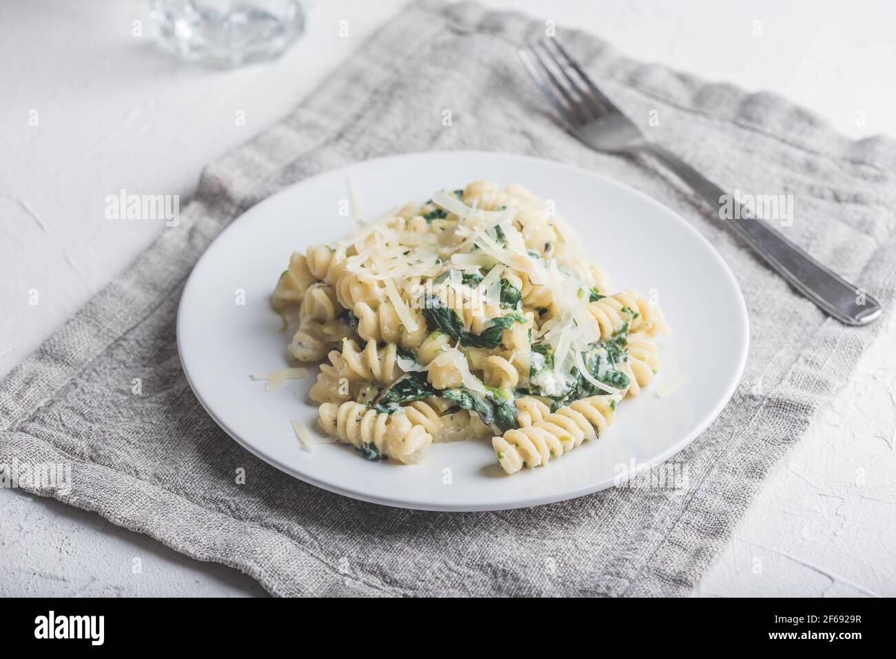 Pasta cremosa di Fusilli di spinaci con ricotta e parmigiano sul Bianco Piastra Foto Stock