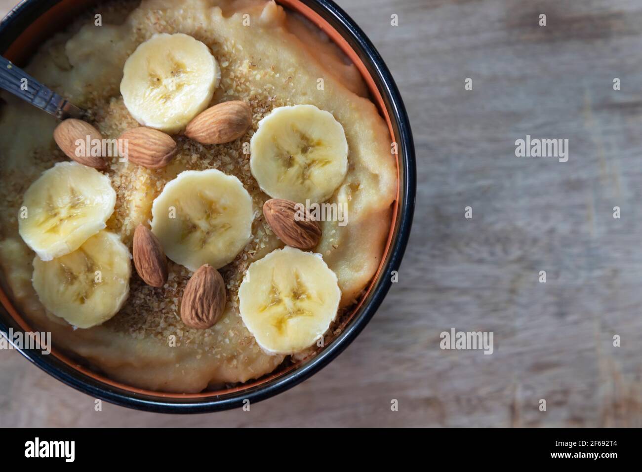 Mandorle e banana con in una ciotola di porridge di farina di mais su una superficie di legno Foto Stock