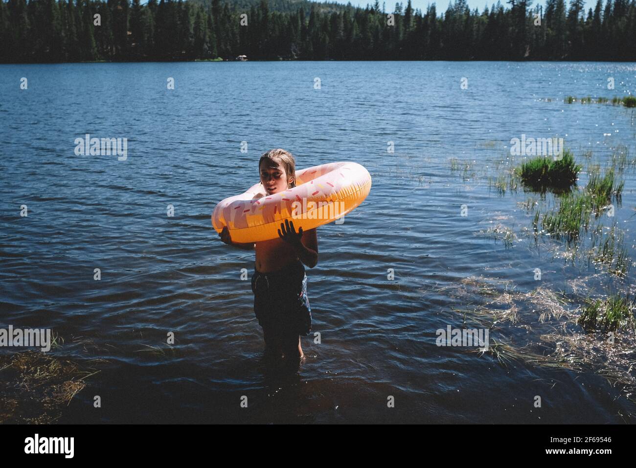 Tween stare su un lago con ciambella gonfiabile intorno a lui collo Foto Stock