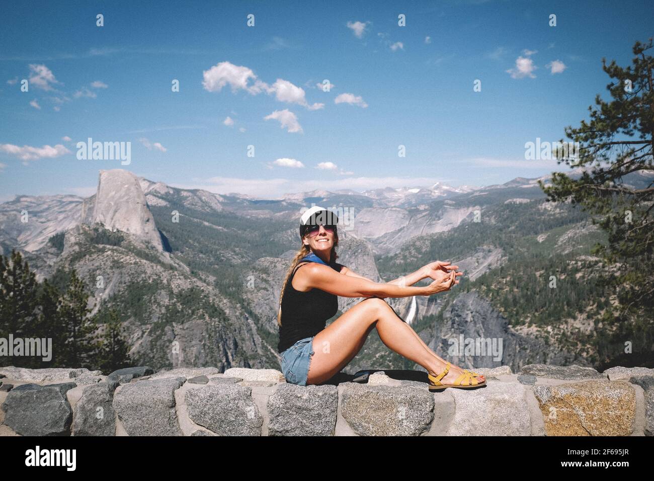 Donna pone per una foto su un muro sopra Yosemite Valle Foto Stock