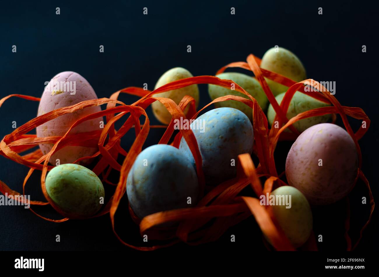 uova di pasqua in nastro arancione su sfondo nero Foto Stock