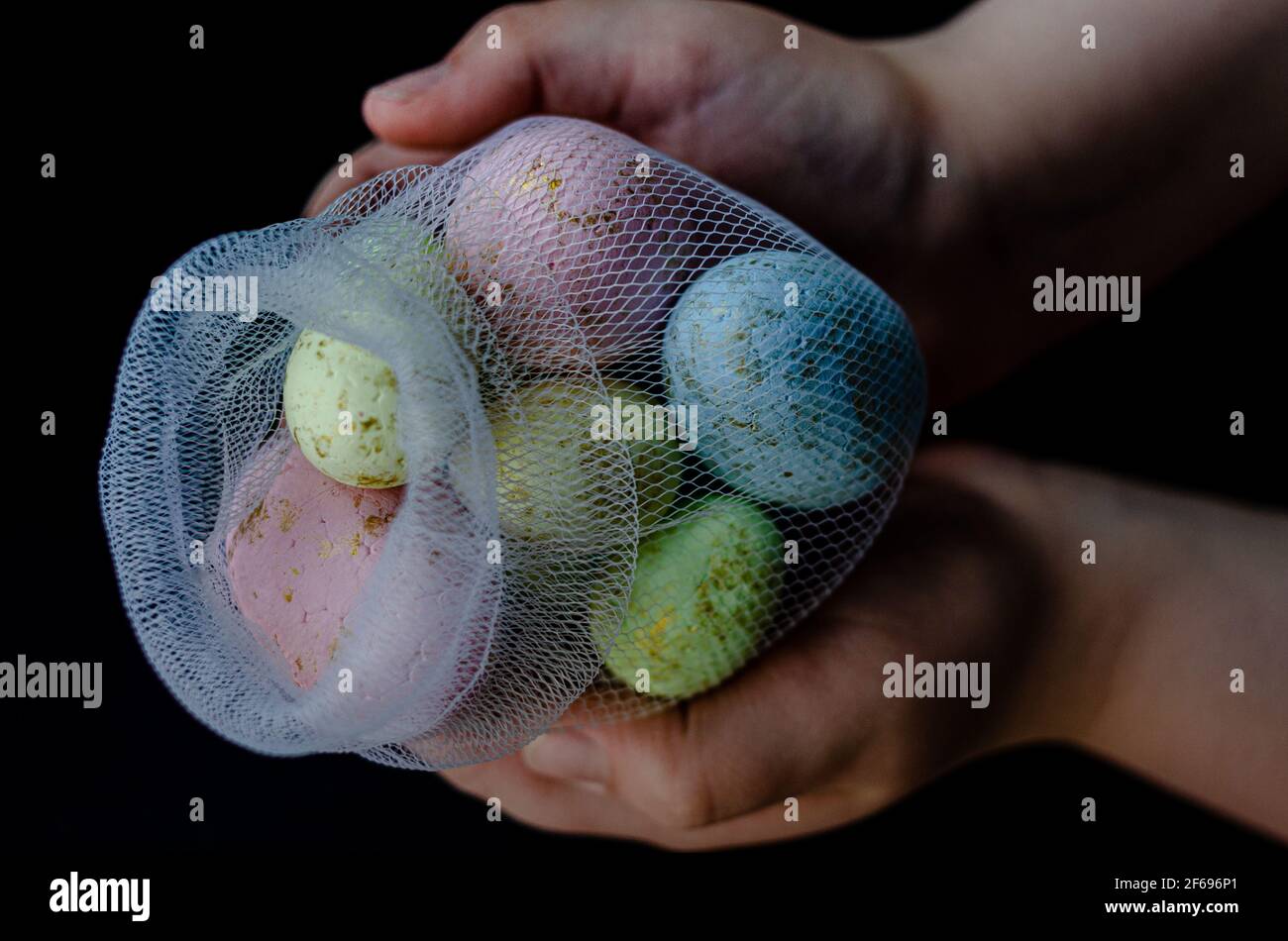 uova di pasqua in una rete, in mani, primo piano Foto Stock