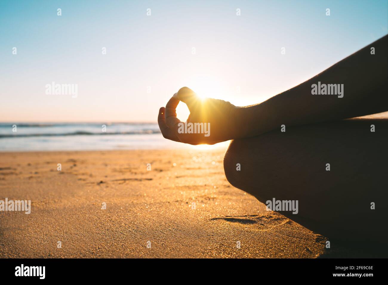 Meditazione sulla spiaggia all'alba al mattino. Seduta sulla sabbia in posa facile o sukhasana con mudra gyan. Relax e armonia con la natura Foto Stock