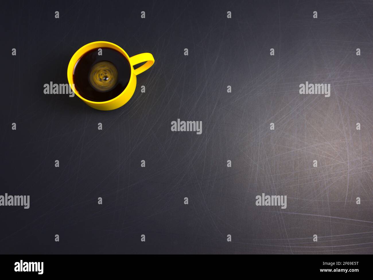 Tazza gialla di caffè nero piatto posare su sfondo nero ruvido graffiato. Consente di copiare lo spazio per il testo, l'immagine o il messaggio. Minimo, vista dall'alto, orizzontale. Foto Stock