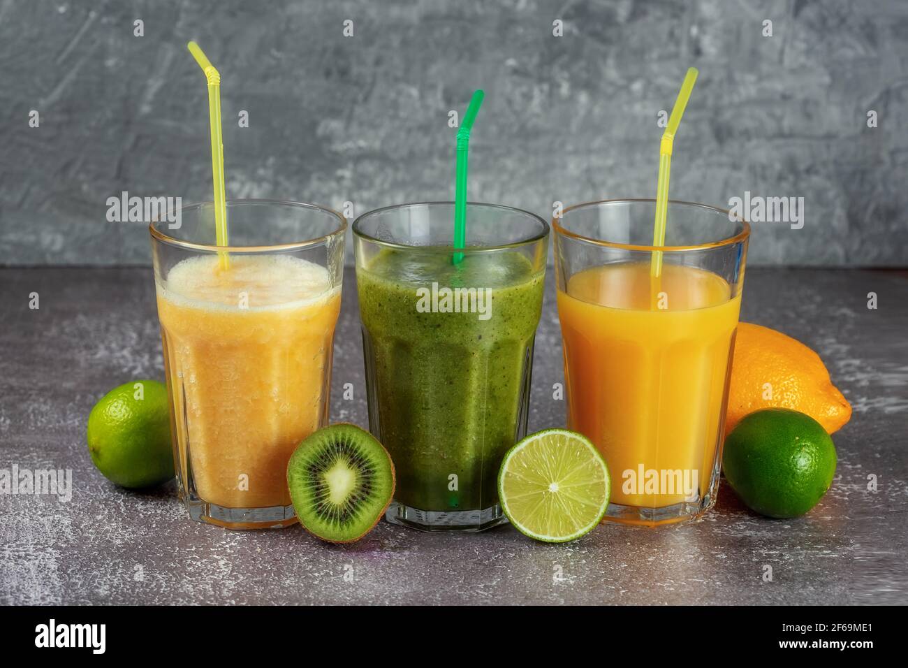 Tre bicchieri di fila con succo d'arancia e banana frullato kiwi arancione Foto Stock