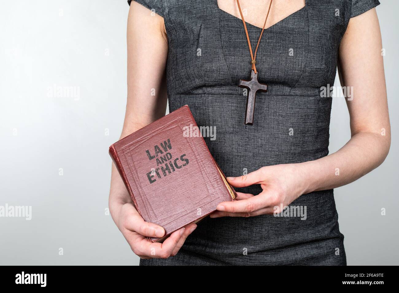 Legge ed Etica. Donna con una croce di legno intorno al collo e un libro in  mani Foto stock - Alamy