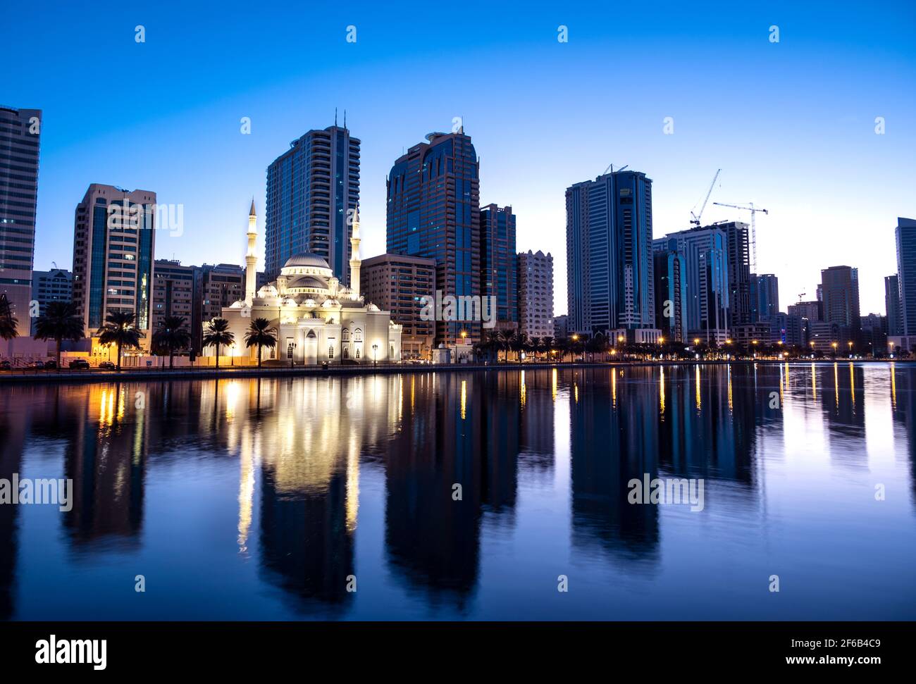 8 gennaio 2021, Sharjah, Emirati Arabi Uniti. Vista panoramica della moschea di al Noor splendidamente illuminata durante le prime ore dell'alba che mostra i riflessi in acqua Foto Stock