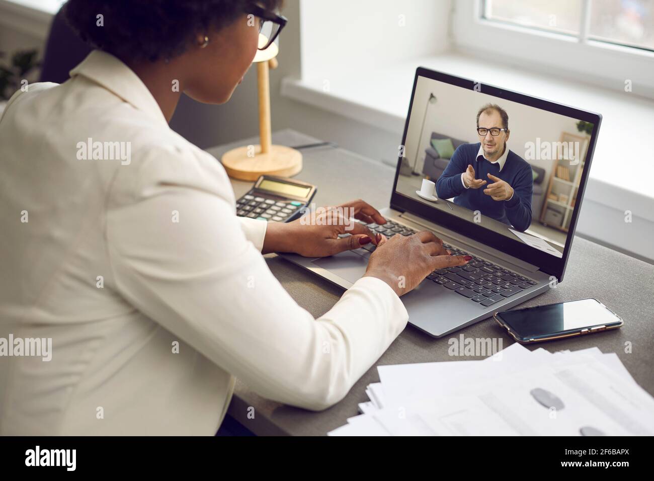 Dipendente che ha una riunione di lavoro online con il suo capo tramite video chiamata su un computer portatile Foto Stock