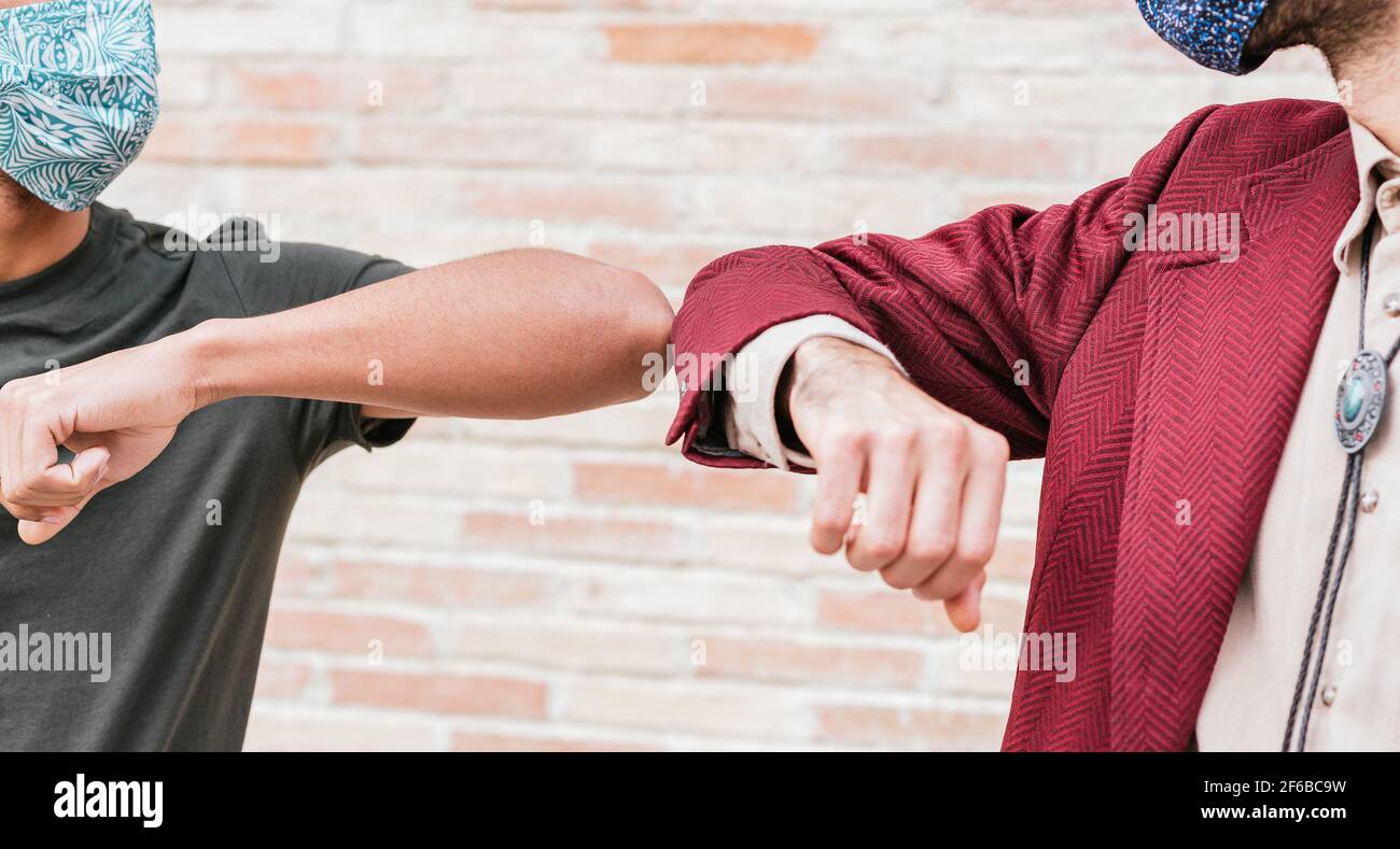 primo piano prendere i gomiti di un caucasico e. amici latinoamericani su un saluto senza contatto con le mani Foto Stock