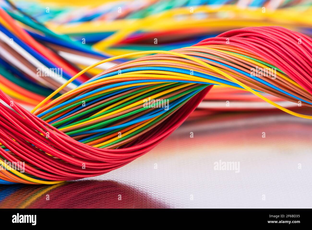 Cavo elettrico e per telecomunicazioni colorato su una superficie metallica lucida con riflessi Foto Stock