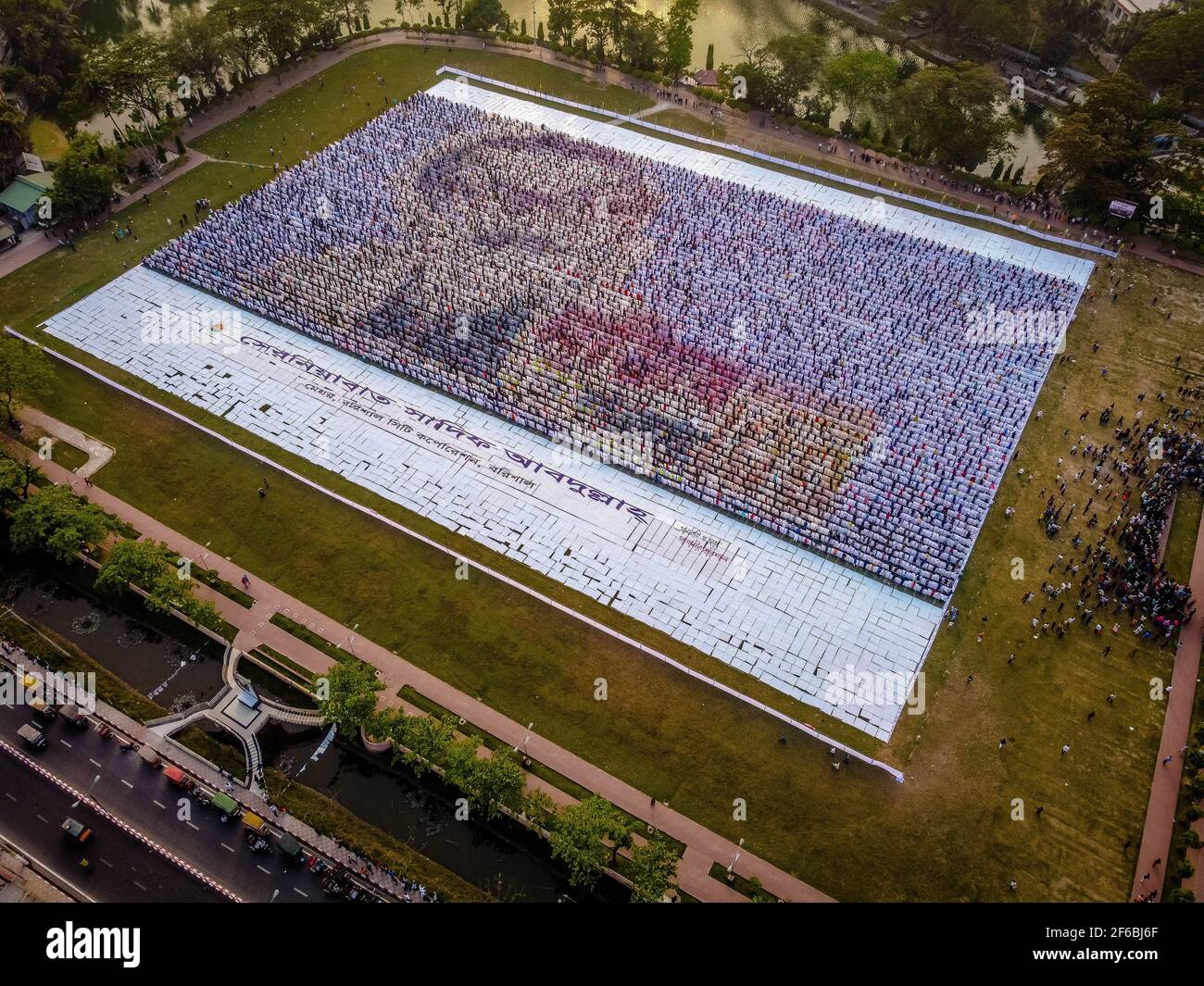 Le persone di Barisal, una città del Bangladesh, hanno realizzato il più grande logo umano in più di 60,000 metri quadrati di area campo per celebrare il 100 ° anno di nascita del Padre della nazione, "Bangabandhu, Sheikh Mujibur Rahman il 30 marzo 2021. Totale 10,050 cartelloni in totale 120 linee, ciascuna delle quali è composta da 84-85 cartelloni, sono utilizzati per realizzare il logo umano più lungo e più grande. Minimo 100-120 lavoratori hanno lavorato duramente fino a 12-13 giorni per fare questo logo gigante e circa 10000 persone si sono levate in piedi alla volta con i cartelli nelle loro mani per rendere il logo con successo per essere visibile. (Foto di Mustasinur Foto Stock