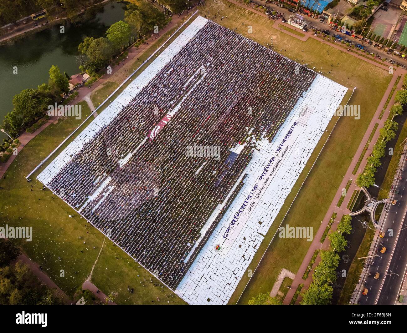 Le persone di Barisal, una città del Bangladesh, hanno realizzato il più grande logo umano in più di 60,000 metri quadrati di area campo per celebrare il 100 ° anno di nascita del Padre della nazione, "Bangabandhu, Sheikh Mujibur Rahman il 30 marzo 2021. Totale 10,050 cartelloni in totale 120 linee, ciascuna delle quali è composta da 84-85 cartelloni, sono utilizzati per realizzare il logo umano più lungo e più grande. Minimo 100-120 lavoratori hanno lavorato duramente fino a 12-13 giorni per fare questo logo gigante e circa 10000 persone si sono levate in piedi alla volta con i cartelli nelle loro mani per rendere il logo con successo per essere visibile. (Foto di Mustasinur Foto Stock