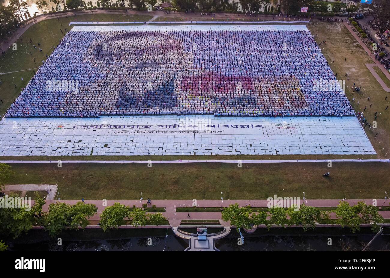 Le persone di Barisal, una città del Bangladesh, hanno realizzato il più grande logo umano in più di 60,000 metri quadrati di area campo per celebrare il 100 ° anno di nascita del Padre della nazione, "Bangabandhu, Sheikh Mujibur Rahman il 30 marzo 2021. Totale 10,050 cartelloni in totale 120 linee, ciascuna delle quali è composta da 84-85 cartelloni, sono utilizzati per realizzare il logo umano più lungo e più grande. Minimo 100-120 lavoratori hanno lavorato duramente fino a 12-13 giorni per fare questo logo gigante e circa 10000 persone si sono levate in piedi alla volta con i cartelli nelle loro mani per rendere il logo con successo per essere visibile. (Foto di Mustasinur Foto Stock