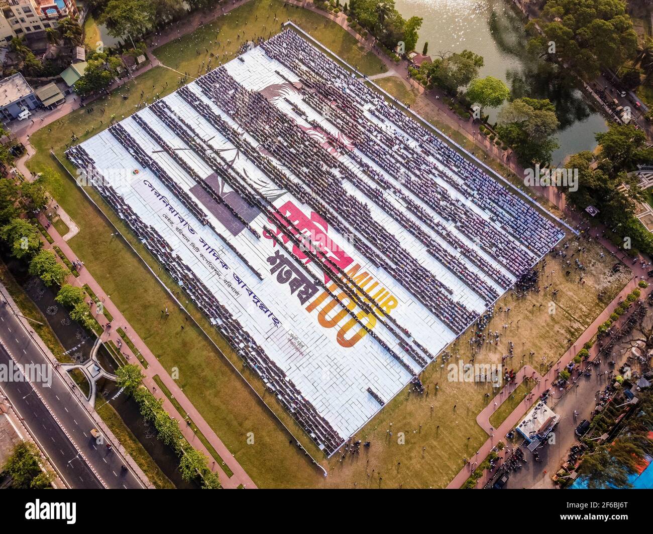 Le persone di Barisal, una città del Bangladesh, hanno realizzato il più grande logo umano in più di 60,000 metri quadrati di area campo per celebrare il 100 ° anno di nascita del Padre della nazione, "Bangabandhu, Sheikh Mujibur Rahman il 30 marzo 2021. Totale 10,050 cartelloni in totale 120 linee, ciascuna delle quali è composta da 84-85 cartelloni, sono utilizzati per realizzare il logo umano più lungo e più grande. Minimo 100-120 lavoratori hanno lavorato duramente fino a 12-13 giorni per fare questo logo gigante e circa 10000 persone si sono levate in piedi alla volta con i cartelli nelle loro mani per rendere il logo con successo per essere visibile. (Foto di Mustasinur Foto Stock