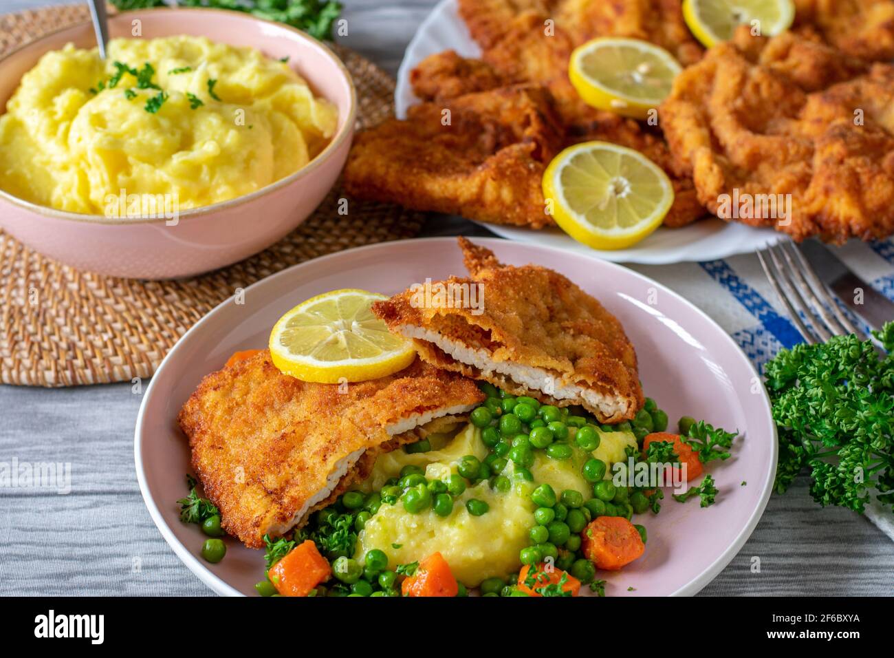 Piatto tradizionale tedesco di maiale schnitzel servito con purè di patate e verdure su un tavolo fisso a casa. Pronto a mangiare Foto Stock
