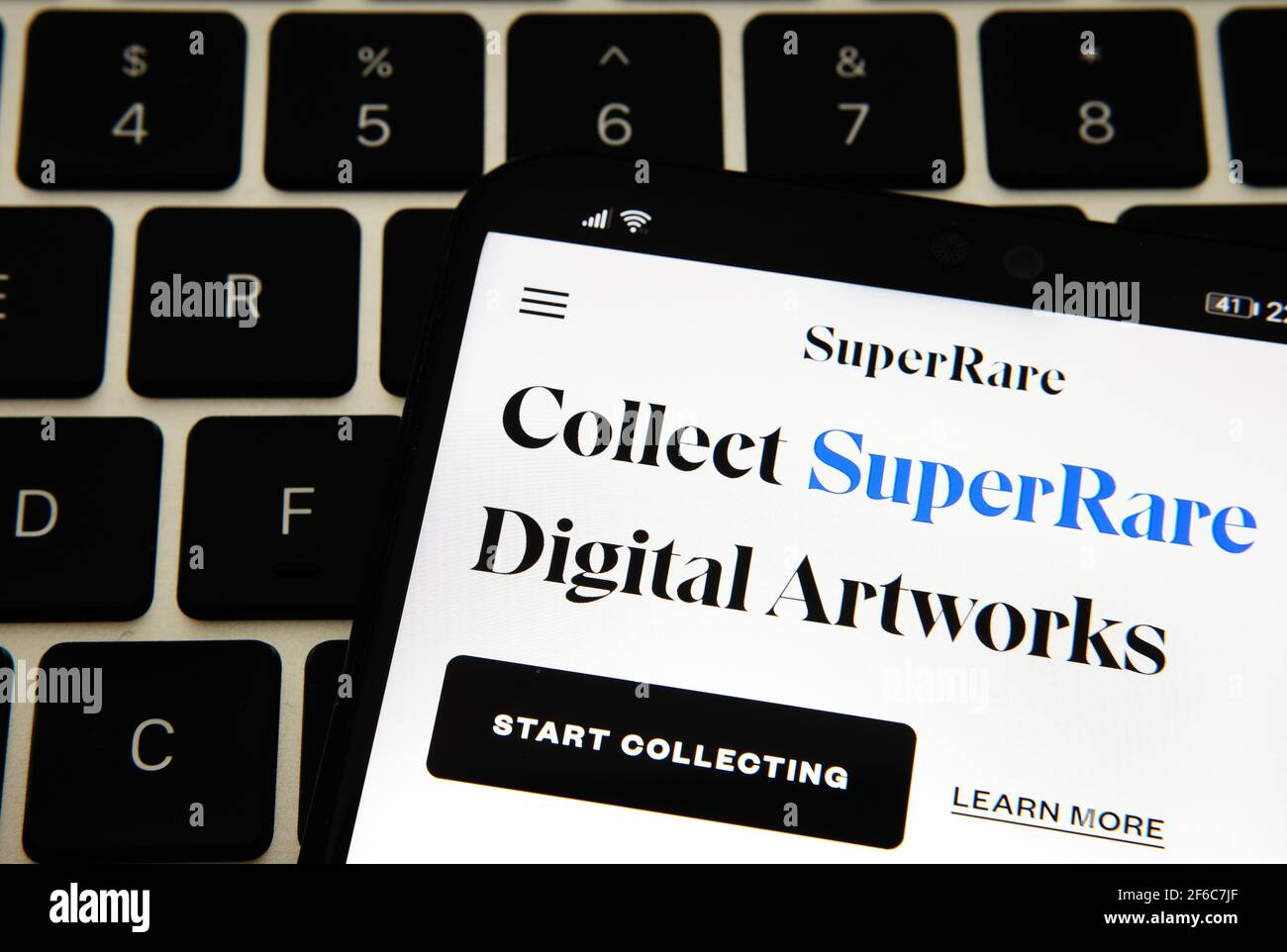 Sito Web SuperRare Digital Artworks visualizzato sullo smartphone posizionato sul computer portatile. Super Rare è un mercato NFT per i creatori di vendere e acquistare non-fungibile Foto Stock