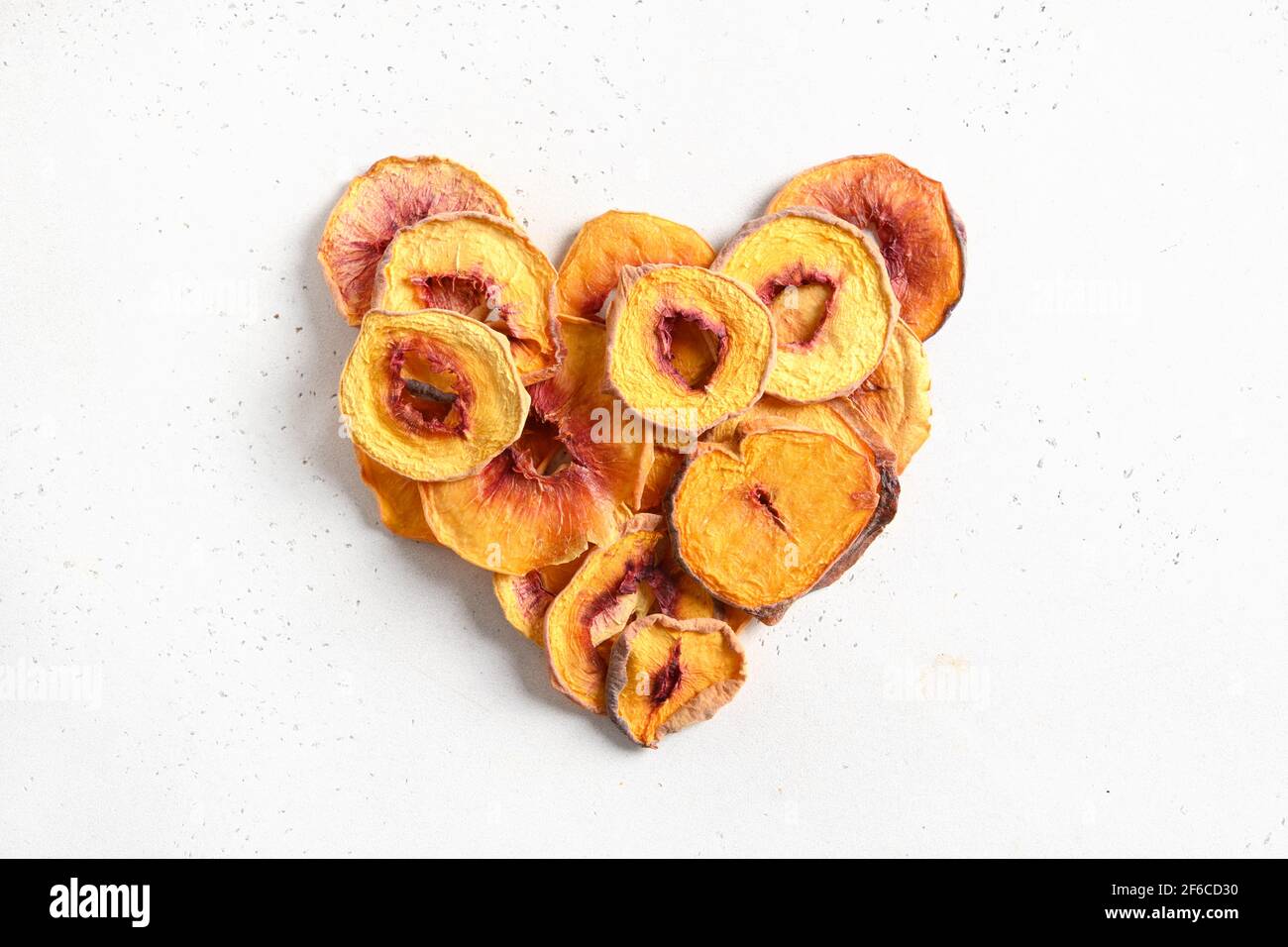 Cuore di pesca secca a fette isolato su fondo bianco. Snack sano cibo senza zucchero. Vista dall'alto. Foto Stock