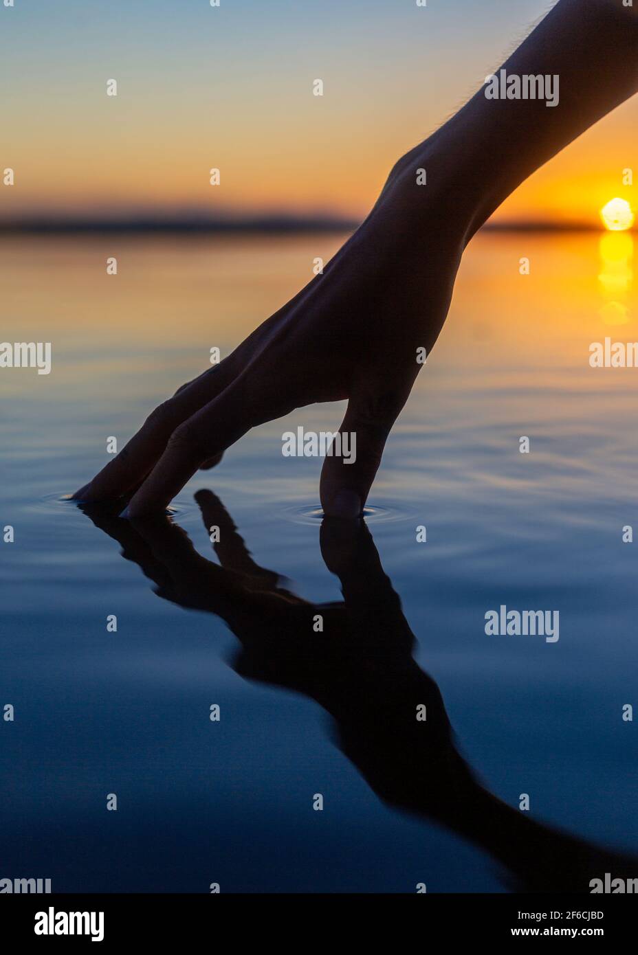 La mano delle ragazze tocca l'acqua calma o il lago Weyba, Sunshine Coast, Queensland, Australia Foto Stock