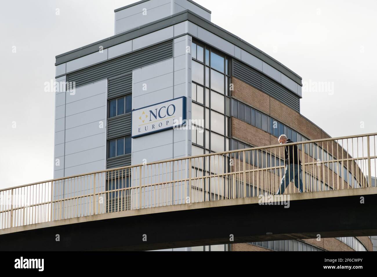 Preston, Lancashire, Regno Unito. Uomo che attraversa il ponte con l'edificio NCO Europe sullo sfondo. Foto Stock