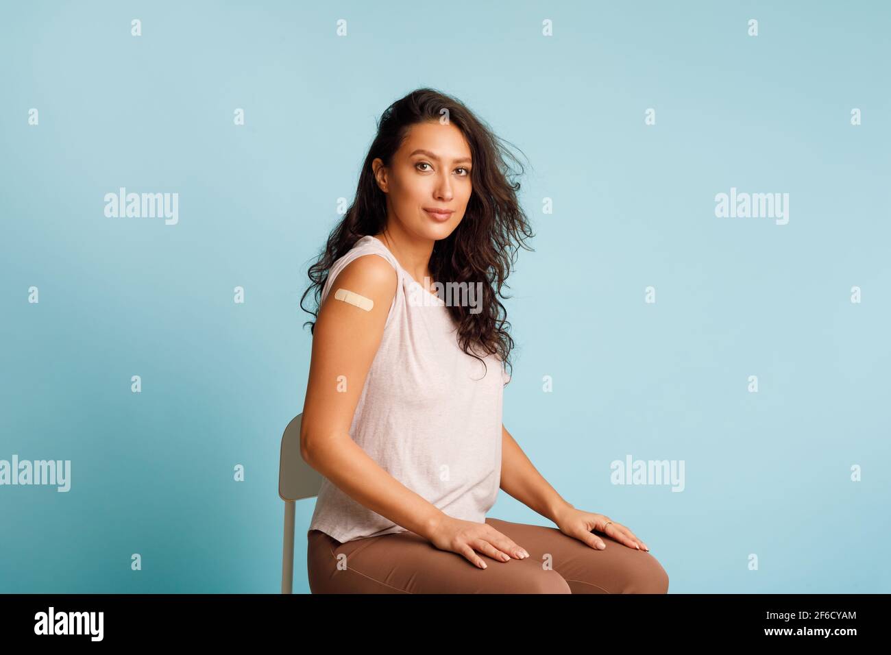 Donna vaccinata che mostra braccio seduta con le maniche arrotolate, studio Foto Stock