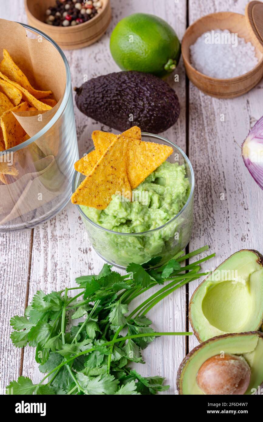 Salsa di guacamole ingredienti avocado, cipolla rossa, coriandolo, lime su tavola rustica in legno. Preparazione degli alimenti Foto Stock