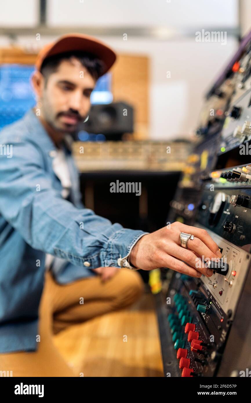 Foto d'inventario dell'hipster man utilizzando il pannello di controllo in studio di musica professionale. Foto Stock