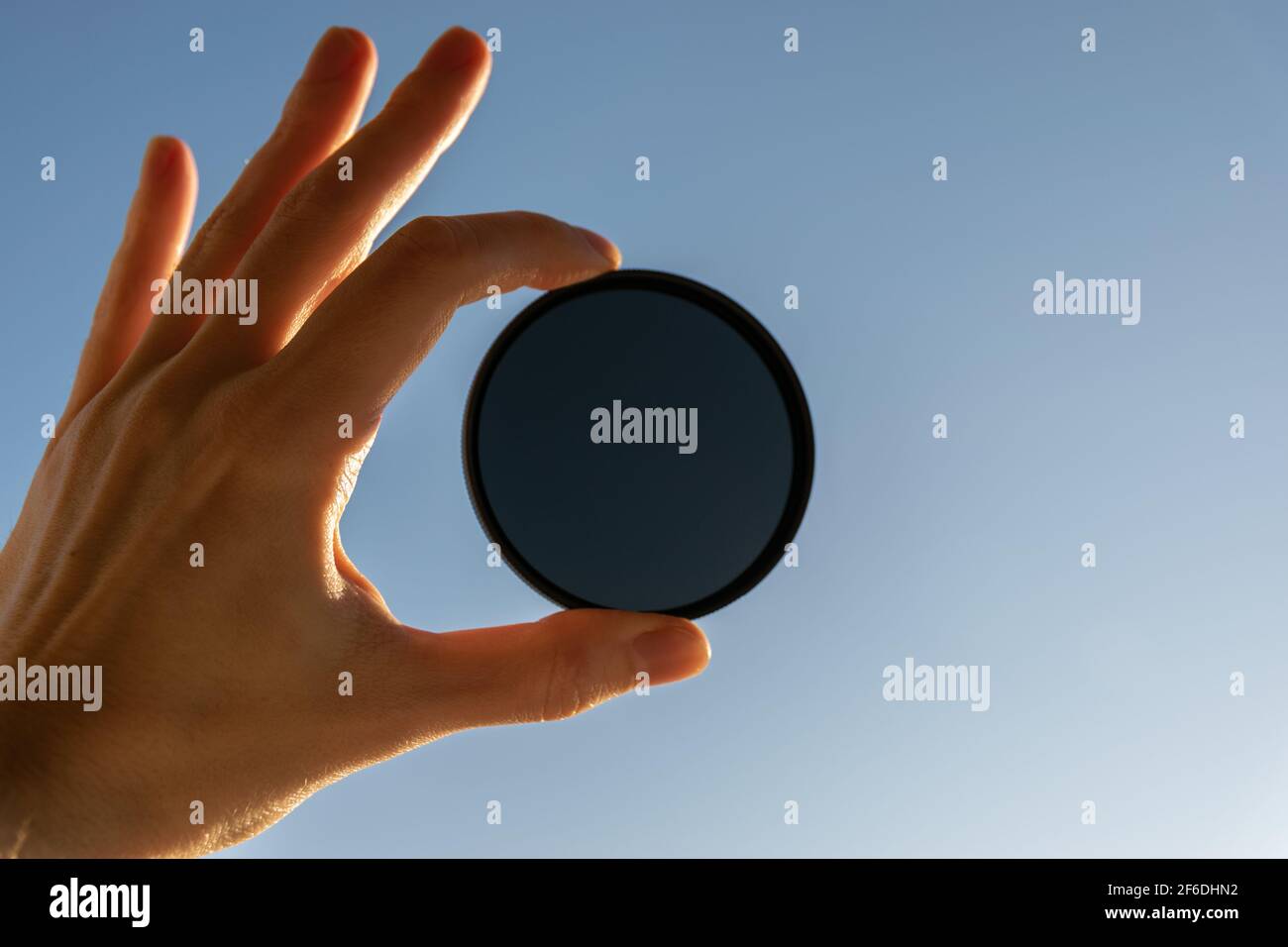 Tieni la mano filtro ND su sfondo blu. Foto Stock