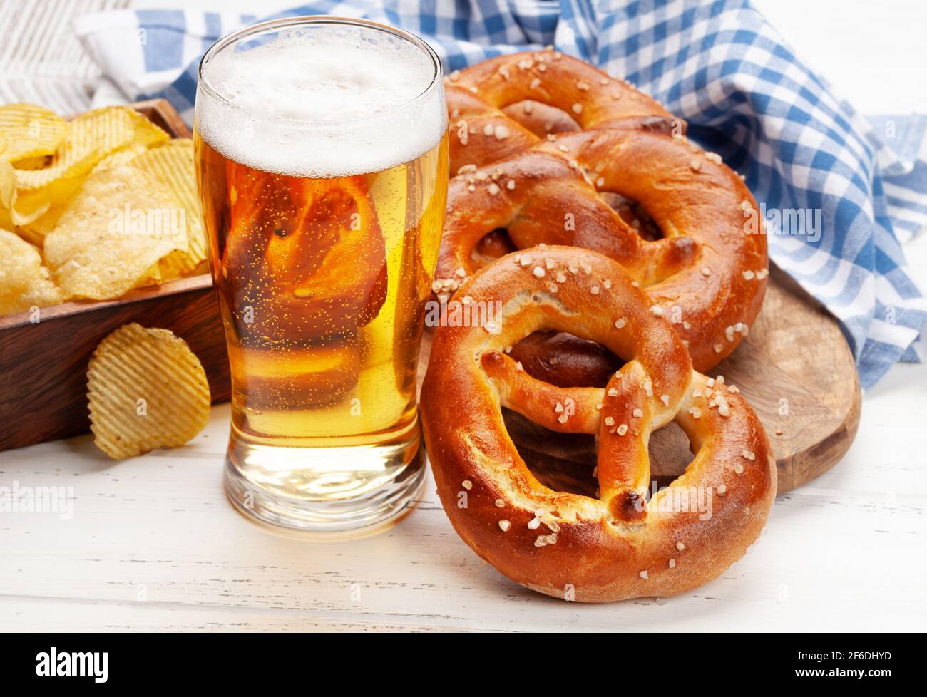 Tazza di birra lager, patatine fritte e pretzel fatto in casa appena sfornato con sale marino su tavolo di legno. Classico spuntino con birra Foto Stock