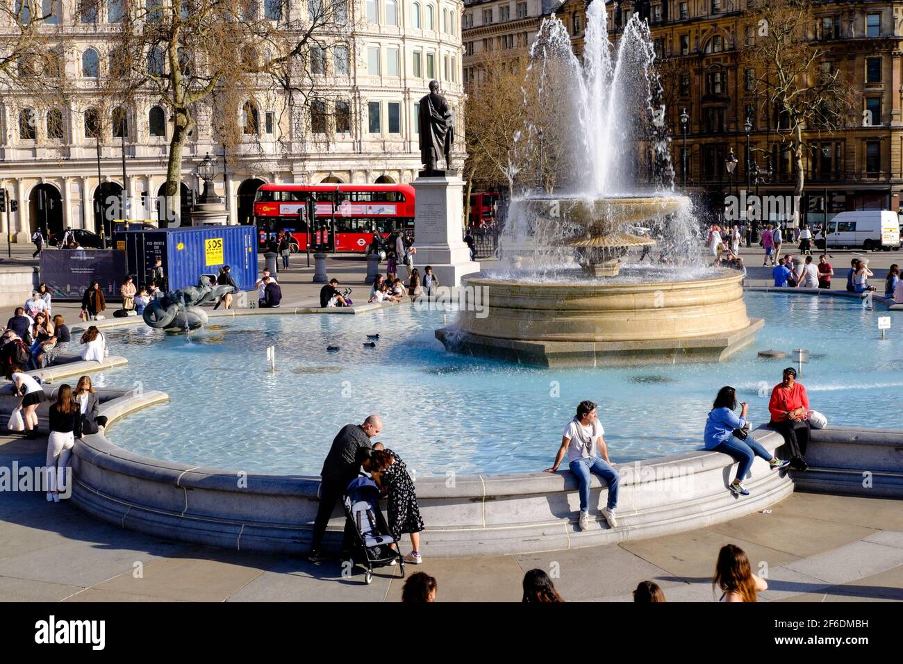 Le persone che godono del sole primaverile in Trafalgar Square di Londra dopo l'allentamento da parte del governo britannico delle restrizioni di Covid che permettono a gruppi di un massimo di sei persone o due famiglie in Inghilterra di incontrarsi all'esterno. Foto Stock