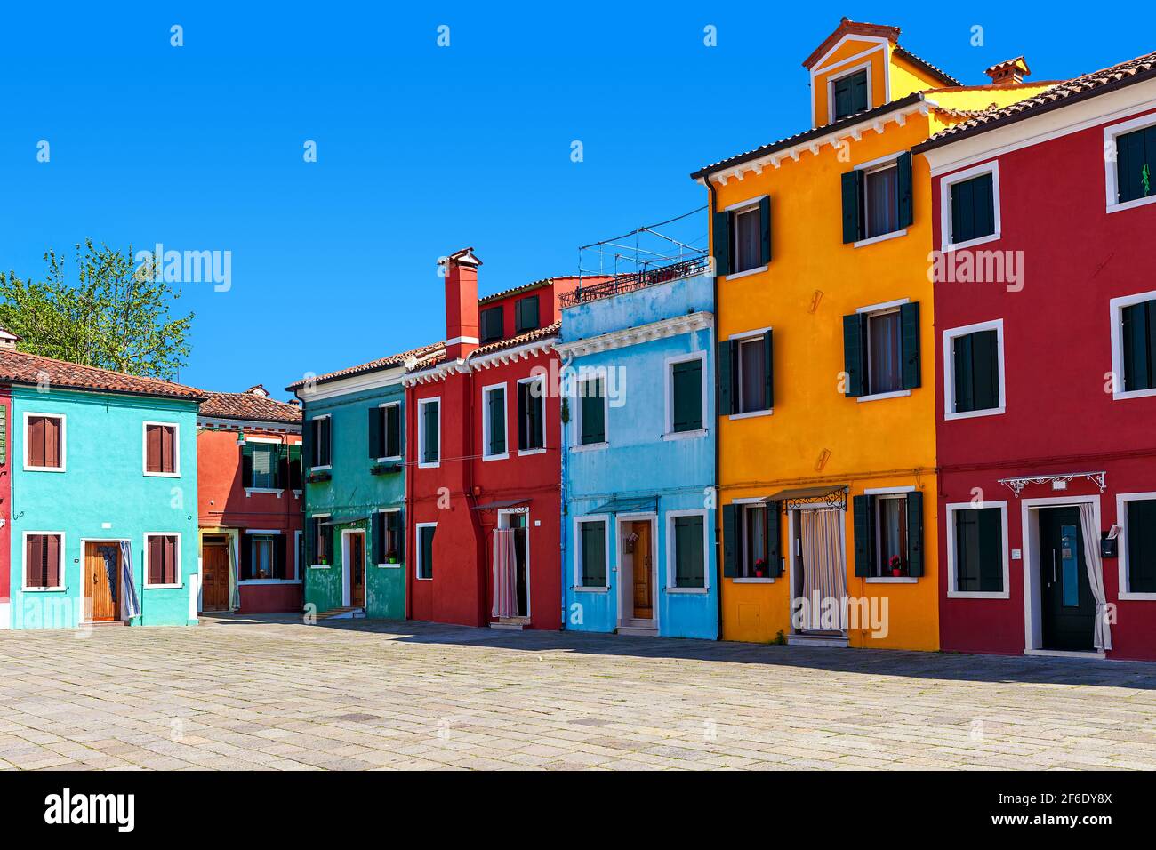 Piccolo cortile e case colorate sotto il cielo blu a Burano, Italia. Foto Stock
