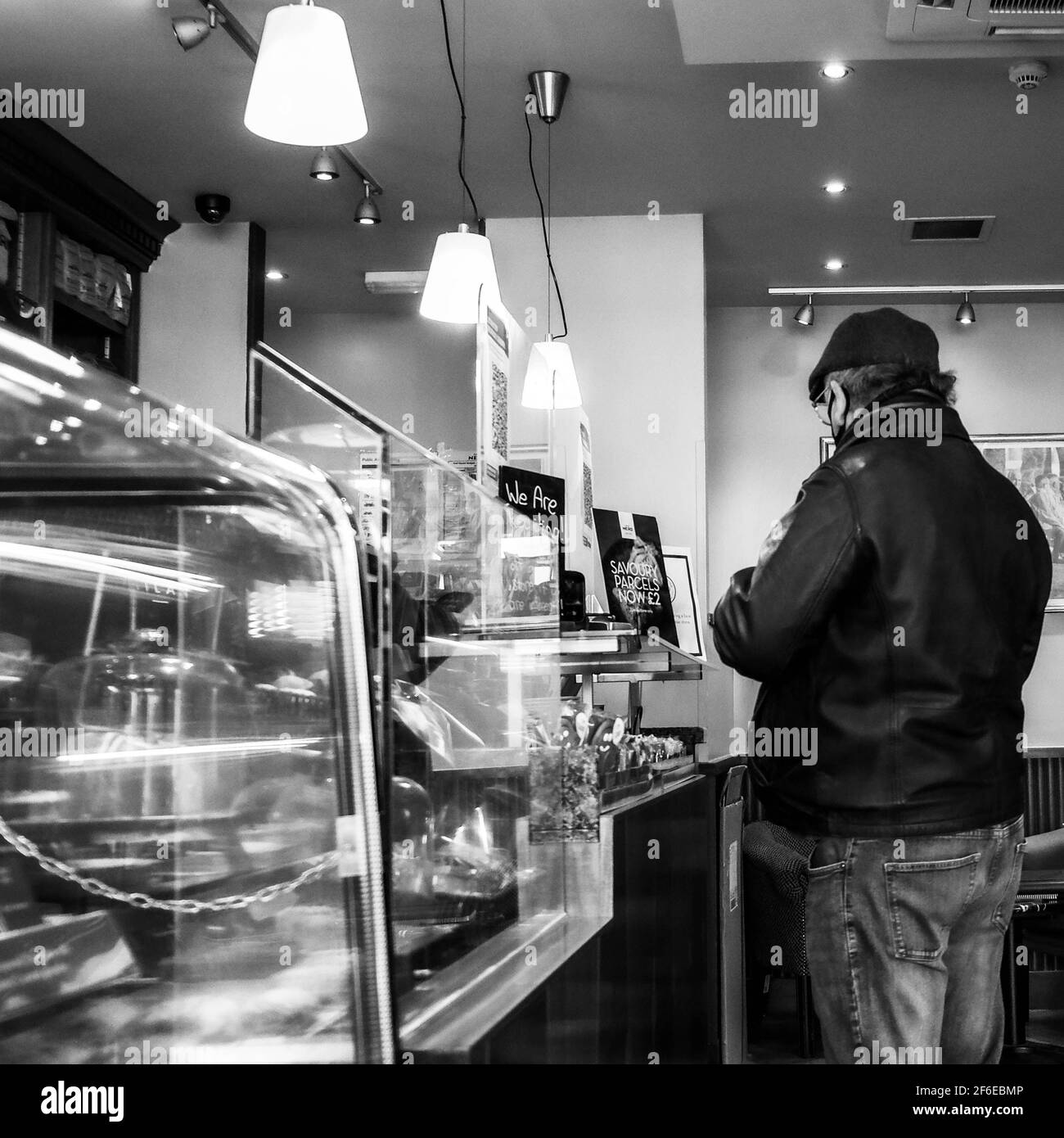 Immagine in bianco e nero di un uomo in piedi Un banco Cafe Nero che acquista UN caffè Takeaway Foto Stock