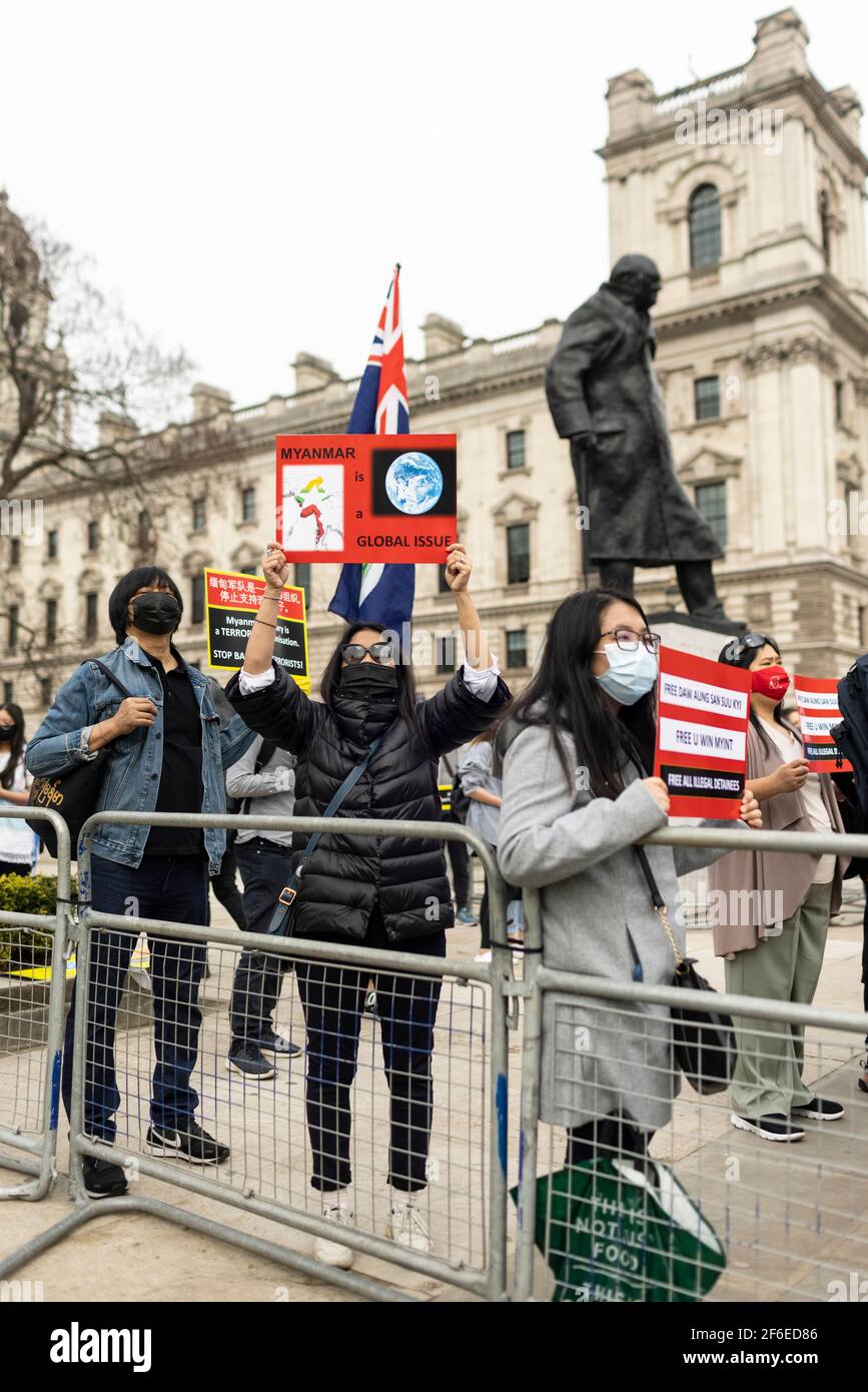 Londra, Regno Unito. 31 Marzo 2021. Manifestanti che tengono i cartelli accanto alla statua di Winston Churchill in Piazza del Parlamento. I manifestanti si sono riuniti in Piazza del Parlamento - indossando maschere facciali e osservando le distanze sociali - prima di marciare all'ambasciata cinese in solidarietà con il popolo del Myanmar contro il colpo di stato militare e le uccisioni di civili. I discorsi sono stati fatti fuori dall'ambasciata. Dall'inizio del colpo di stato militare del 1° febbraio, oltre 520 persone sono state uccise in Myanmar dalle forze di sicurezza. Sabato scorso è stato il giorno più violento in cui sono state uccise più di 100 persone. Credi Foto Stock