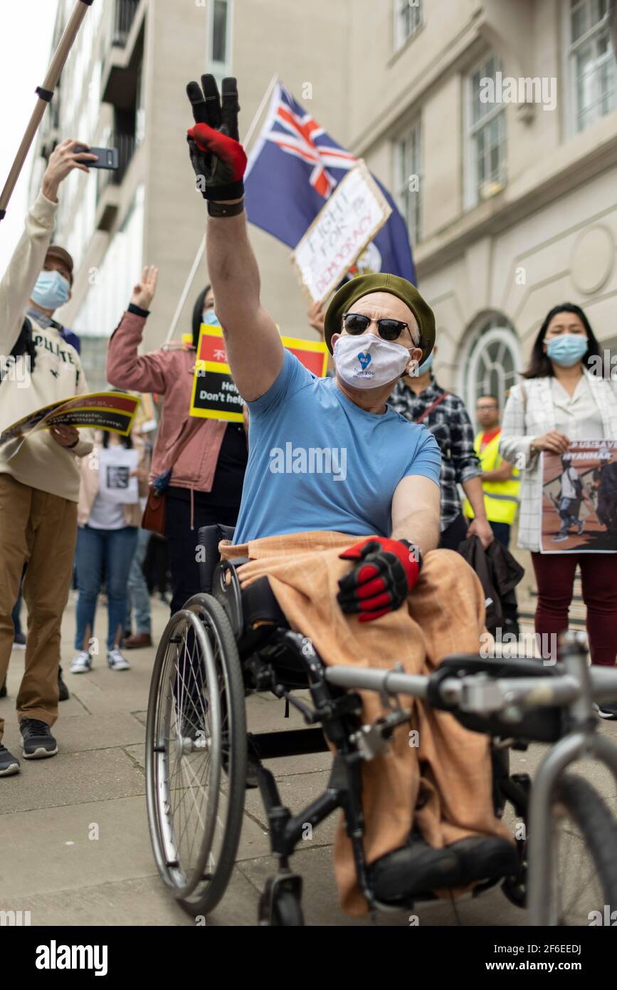 Londra, Regno Unito. 31 Marzo 2021. Un uomo disabile mostra il suo sostegno e fa il saluto a tre dita della resistenza. I manifestanti si sono riuniti in Piazza del Parlamento - indossando maschere facciali e osservando le distanze sociali - prima di marciare all'ambasciata cinese in solidarietà con il popolo del Myanmar contro il colpo di stato militare e le uccisioni di civili. I discorsi sono stati fatti fuori dall'ambasciata. Dall'inizio del colpo di stato militare del 1° febbraio, oltre 520 persone sono state uccise in Myanmar dalle forze di sicurezza. Sabato scorso è stato il giorno più violento in cui sono state uccise più di 100 persone. Credito: Foto Stock
