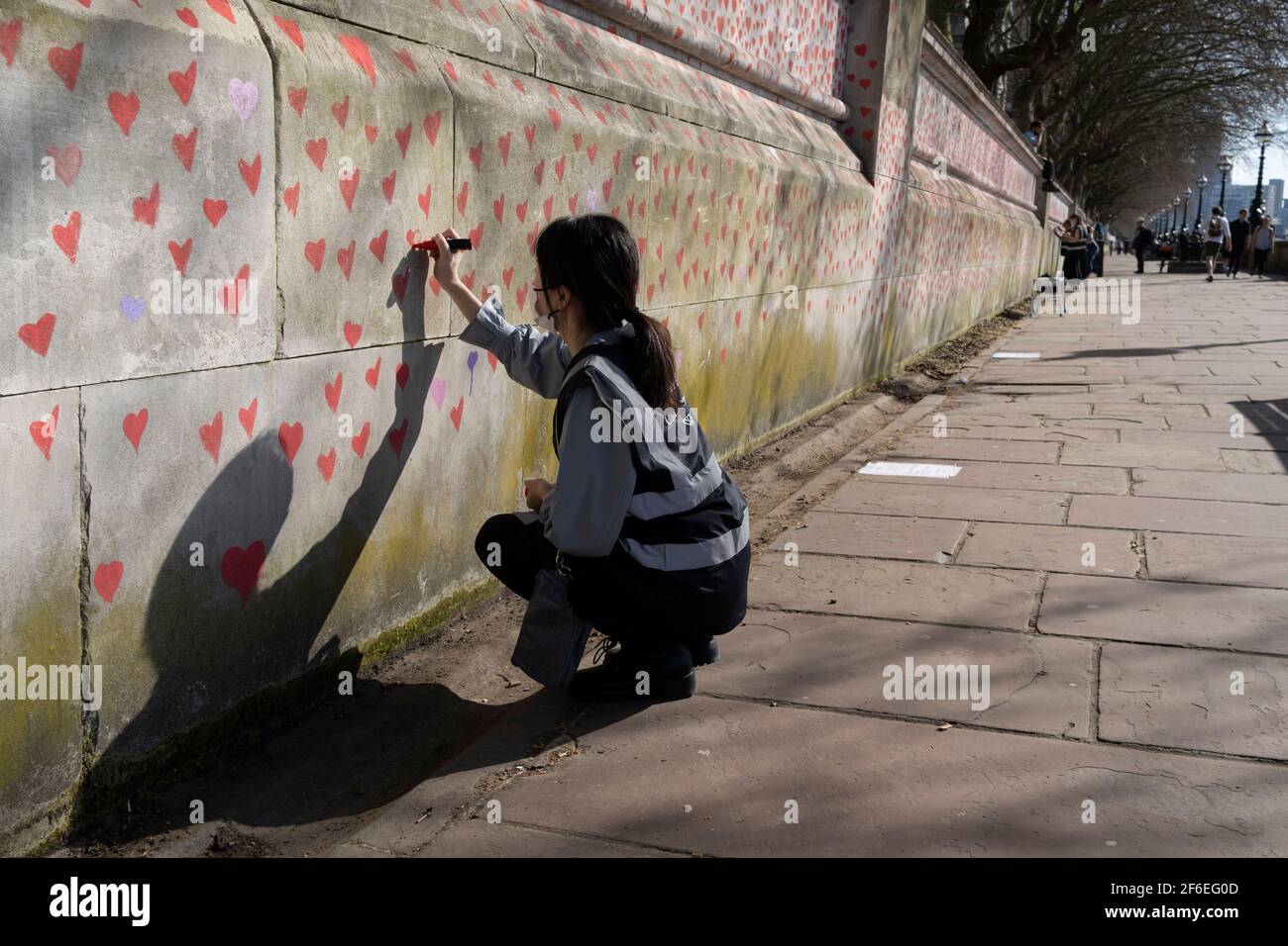I cuori rossi che formano il National Covid Memorial Wall, un tributo alle oltre 150,000 vittime britanniche della pandemia di Coronavirus. La famiglia e gli amici delle vittime di Covid-19 hanno iniziato a lavorare sul muro situato fuori dall'ospedale St Thomas, e che si affaccia alla Camera del Parlamento a Westminster, il 30 marzo 2021, a Londra, Inghilterra. Lo scorso anno il primo Ministro Boris Johnson è stato trattato per Covid a St Thomas. Foto Stock