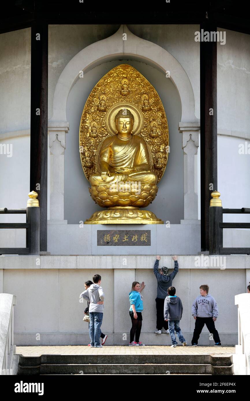 Bambini appesi al Buddha. Una scultura in bronzo dorato del Buddha alla Pagoda della Pace, Battersea Park, Londra. Foto Stock