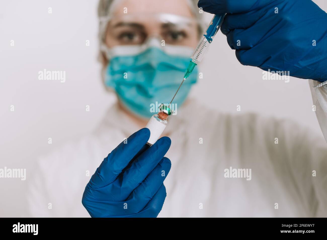 medico femminile con maschera facciale contenente vaccino covid 19 in guanti Foto Stock