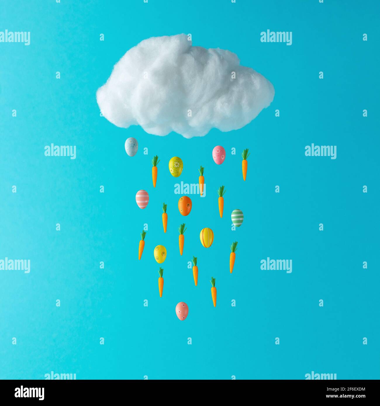 Nube di cotone bianco con uova di Pasqua e carote su sfondo blu. Concetto di vacanza primaverile minimo. Foto Stock